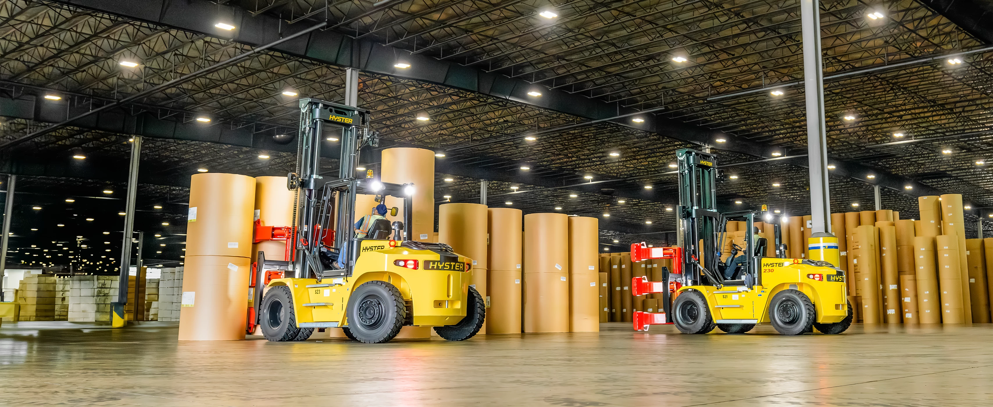 Two Hyster 230 lift trucks with Bolzoni paper roll clamp attachments.