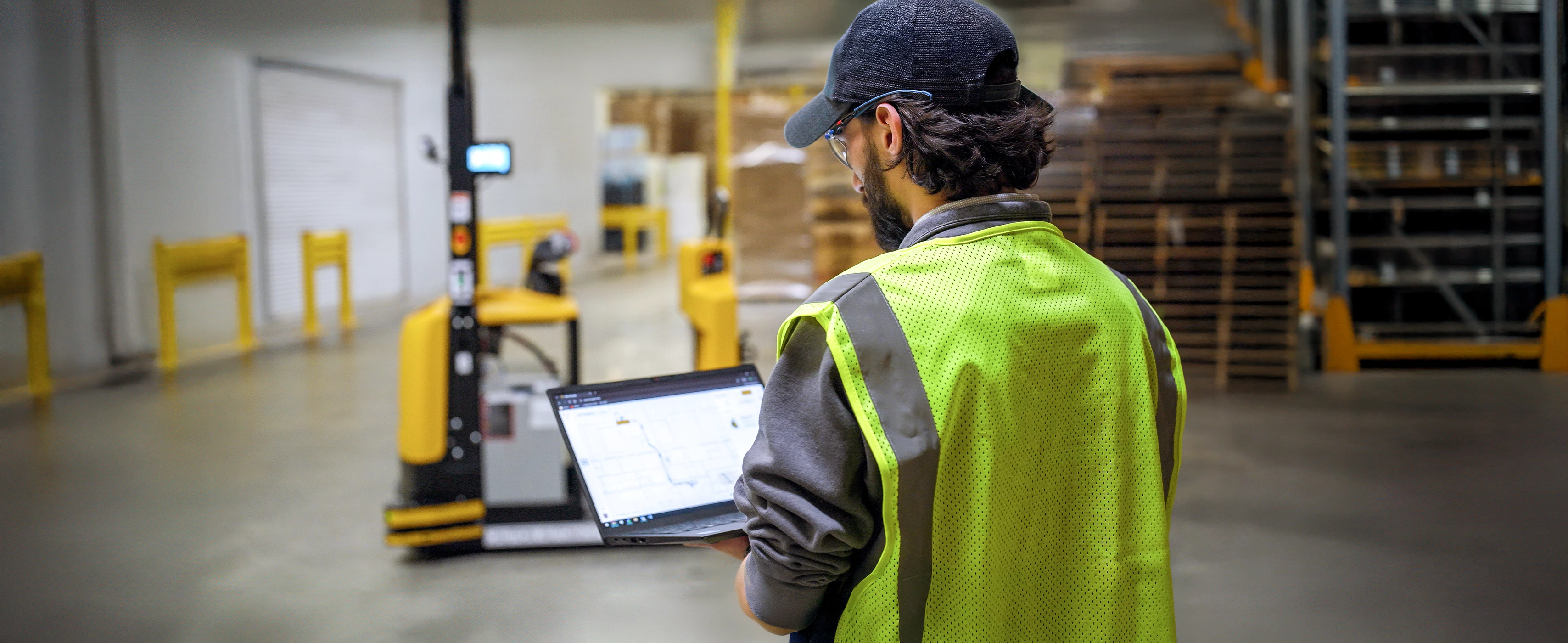 Person on laptop programming Yale Relay automated tow tractor. 