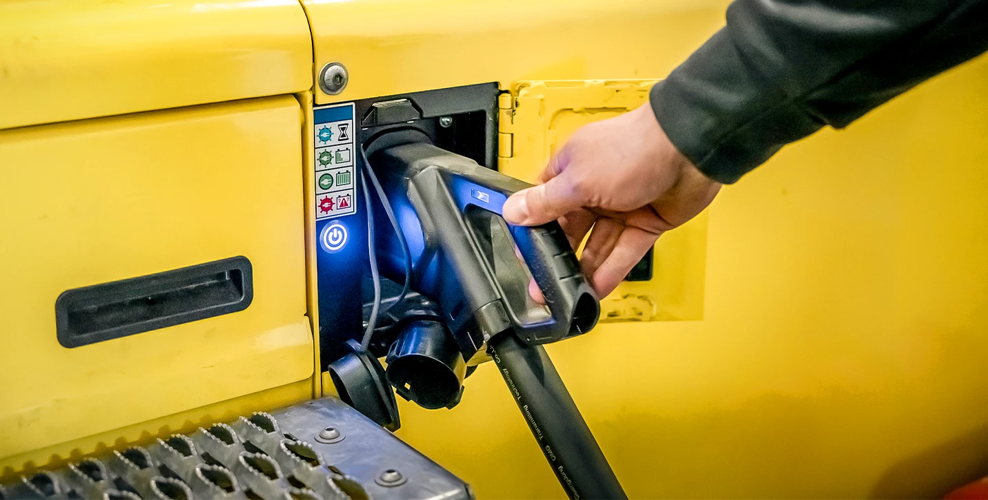 Person plugging in high-capacity electric forklift to charge. 