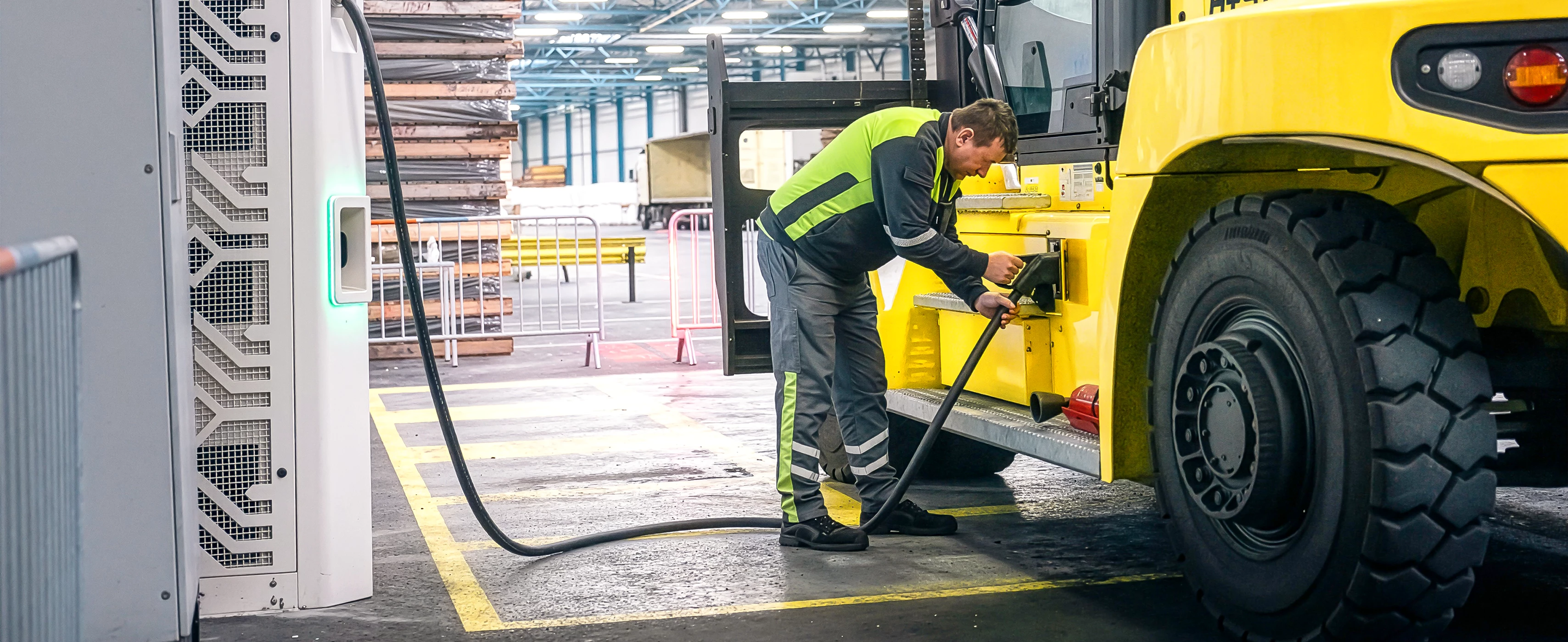 Man plugging Hyster electric big truck into charger.